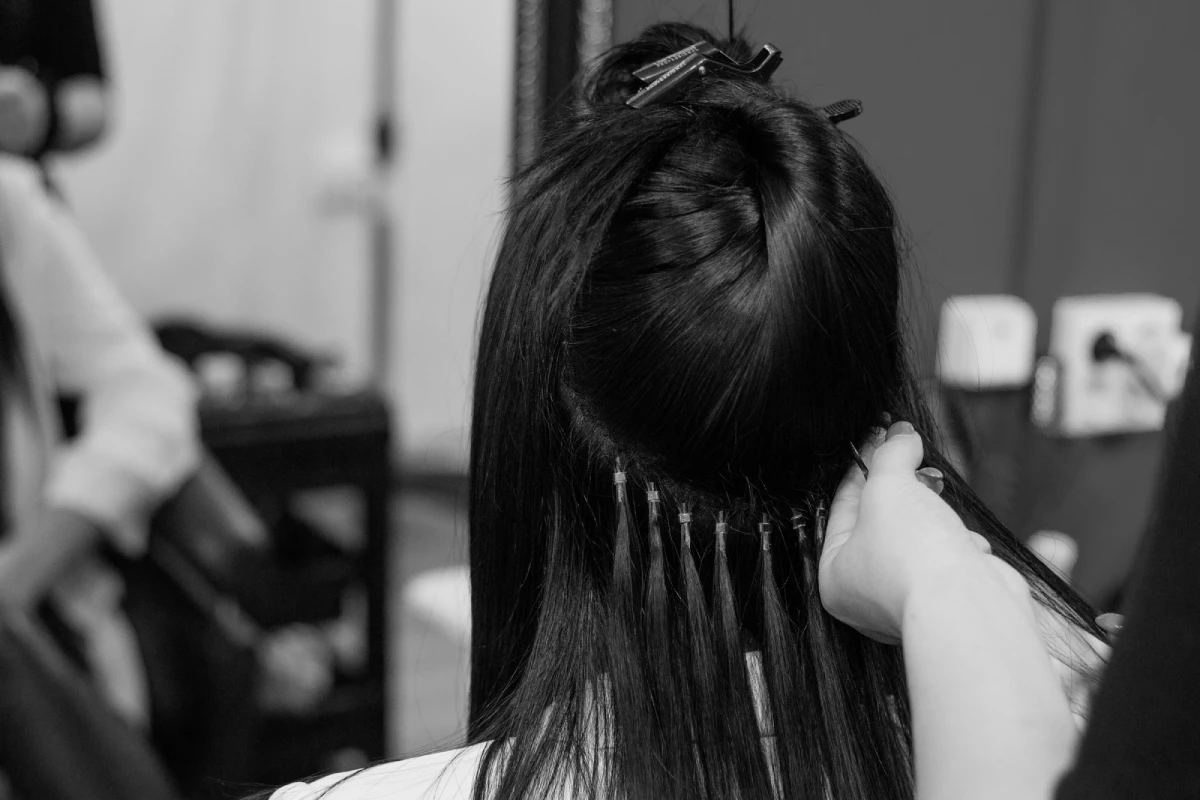 Elevate Your Look with Great Lengths Hair Extensions in Scottsdale, AZ Tabu Salon a person combing hair with hair clips Great Lengths Hair Extensions in Scottsdale, AZ