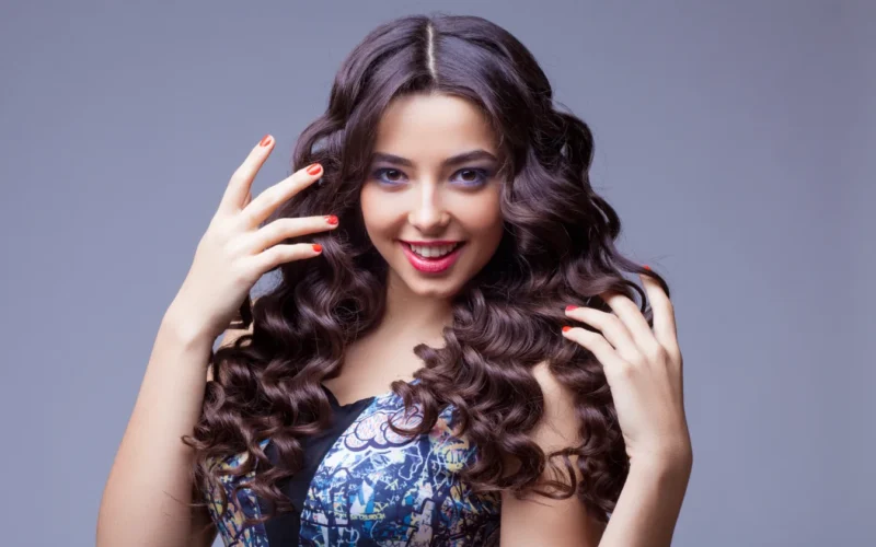 Hand Tied Hair Extensions in Scottsdale Az Tabu Salon A woman with long curly hair and red nails, Hand Tied Hair Extensions in Scottsdale Az