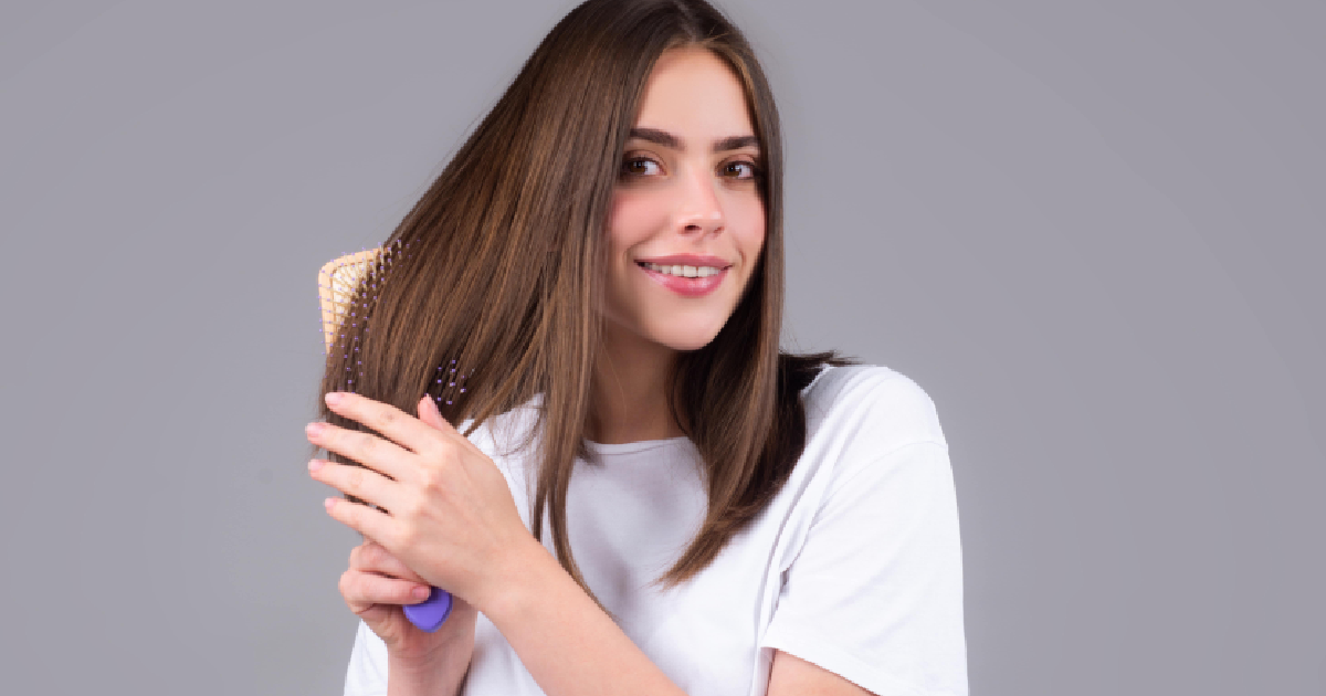 Woman brushing straight, toner-enhanced brown hair and smiling in Scottsdale, AZ.